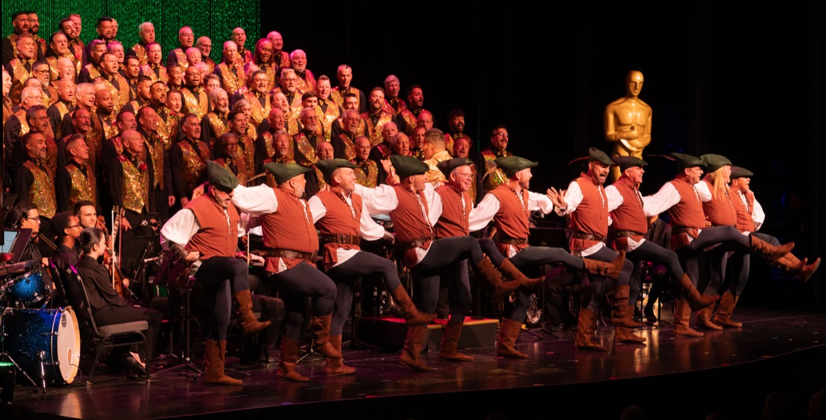 GMCSF chorus performing with dancers and orchestra in a Hollywood-themed concert.